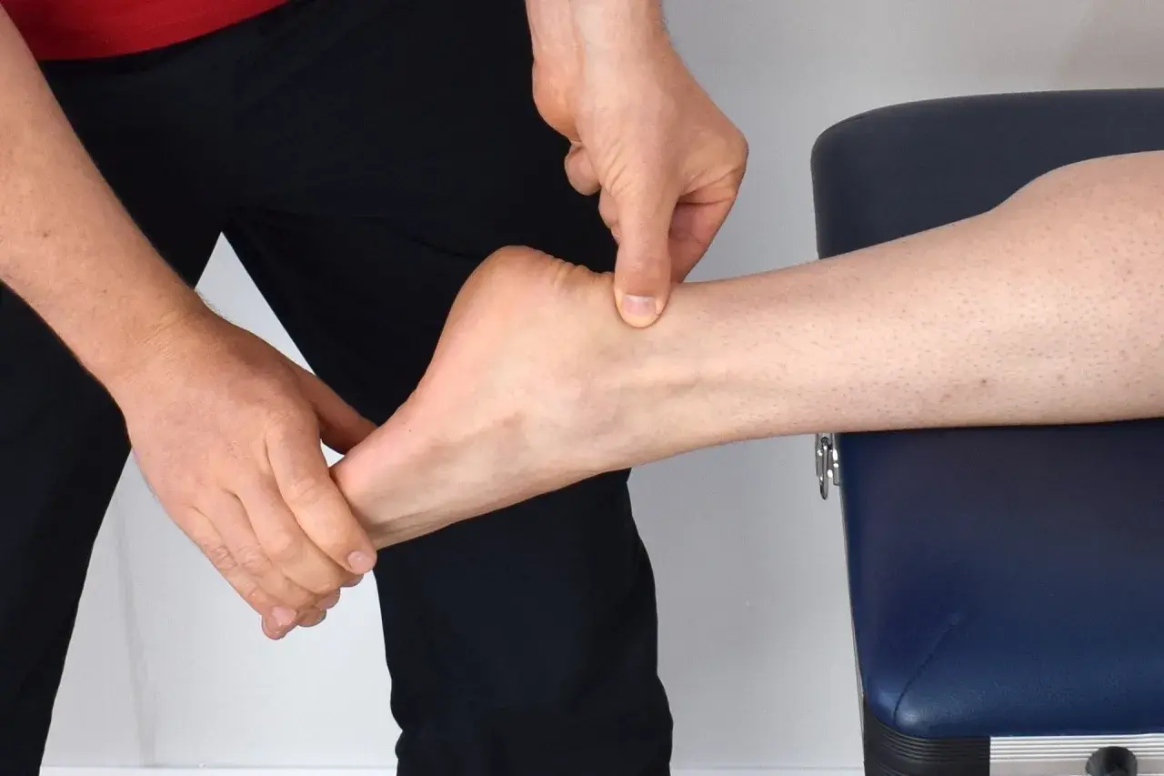 Mains appliquant un massage sur le tendon d'Achille d'une cheville.