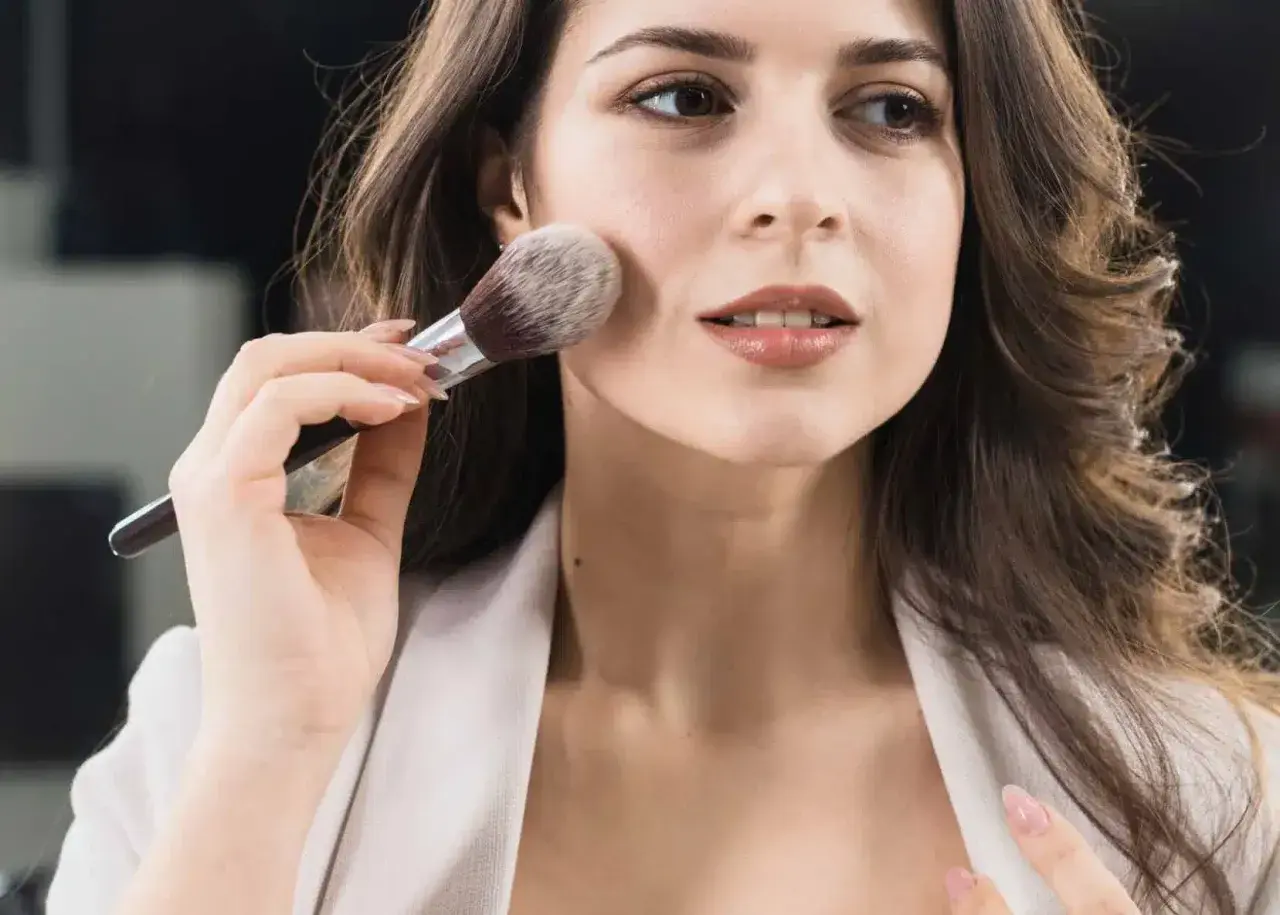 Donna applica il primer con un pennello, creando una base perfetta per il trucco.
