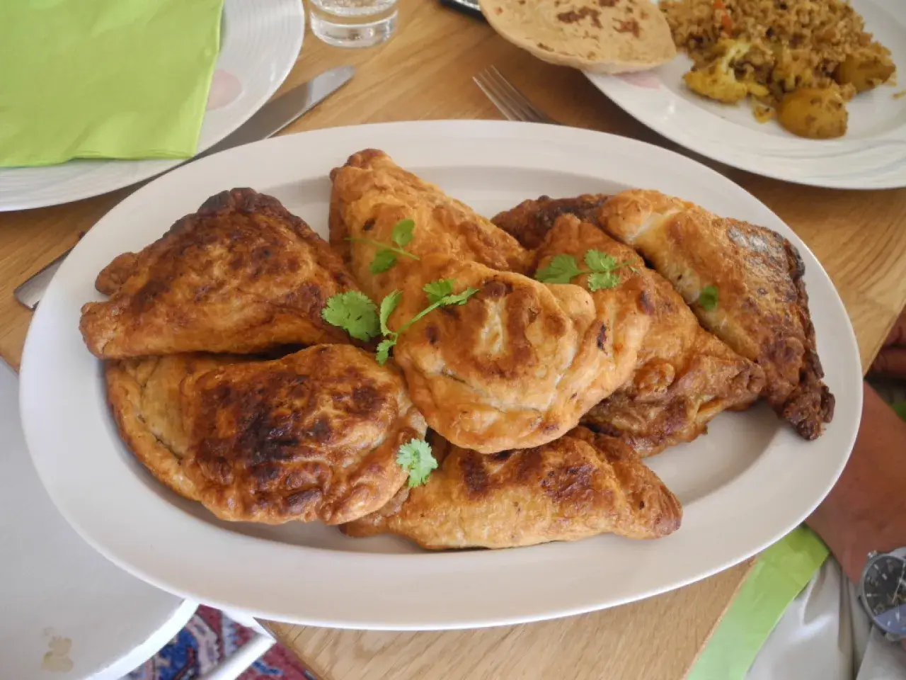 En tallrik med gyllene, friterade samosas, perfekt för ett samosa recept. Garnerade med färsk koriander.