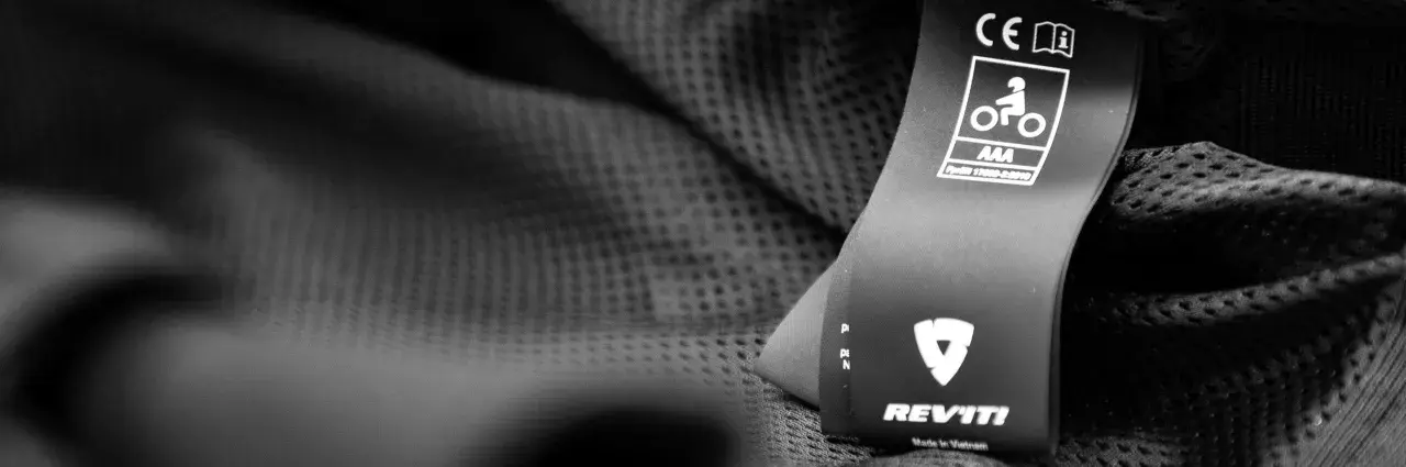 Etichetta con simboli di sicurezza e certificazione casco moto AAA, marchio REV'IT!.
