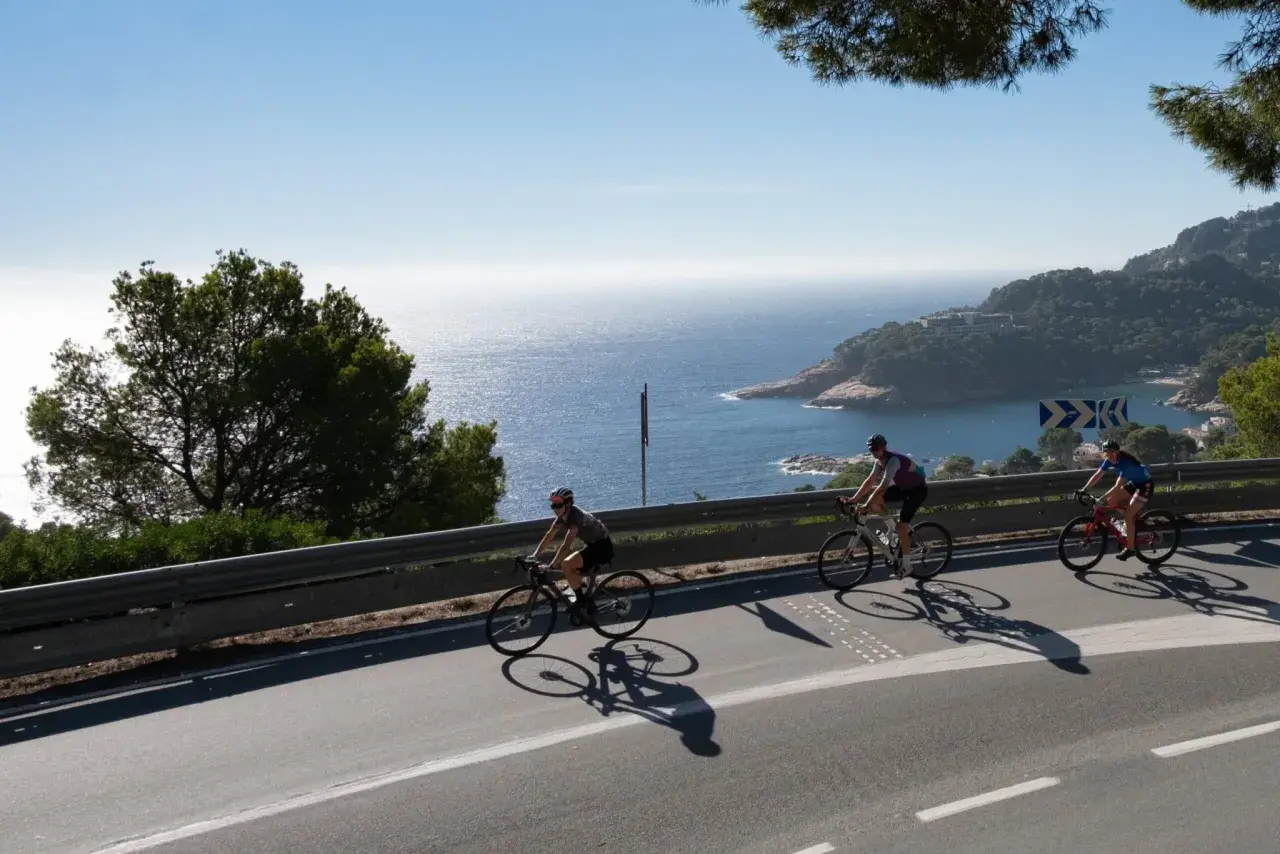 Ciclistas disfrutan del cicloturismo en Girona, con vistas al mar Mediterráneo y la costa.