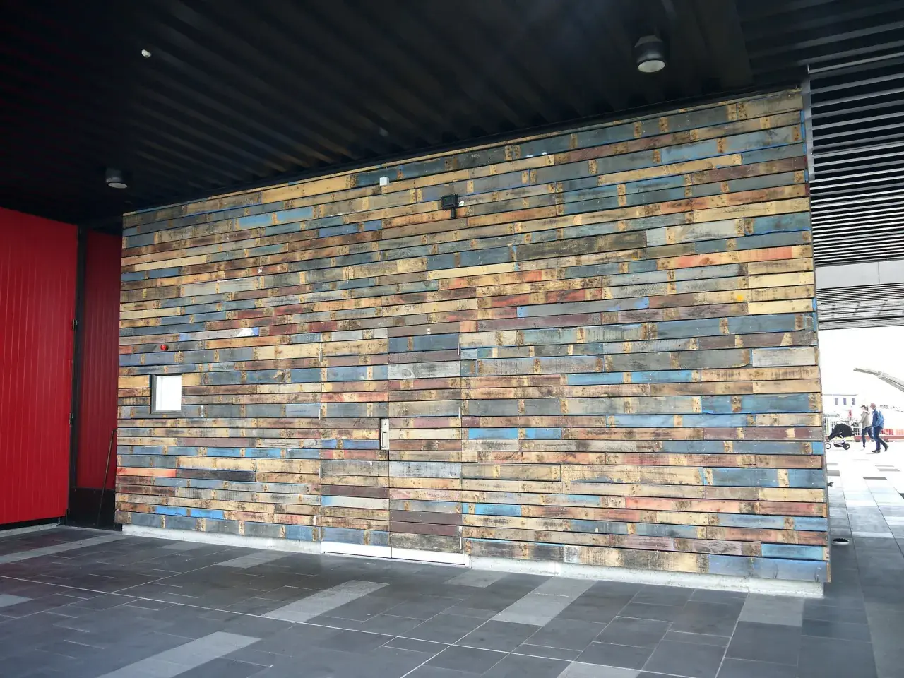 Un mur en palette extérieure aux couleurs vives et variées, créant une texture unique.