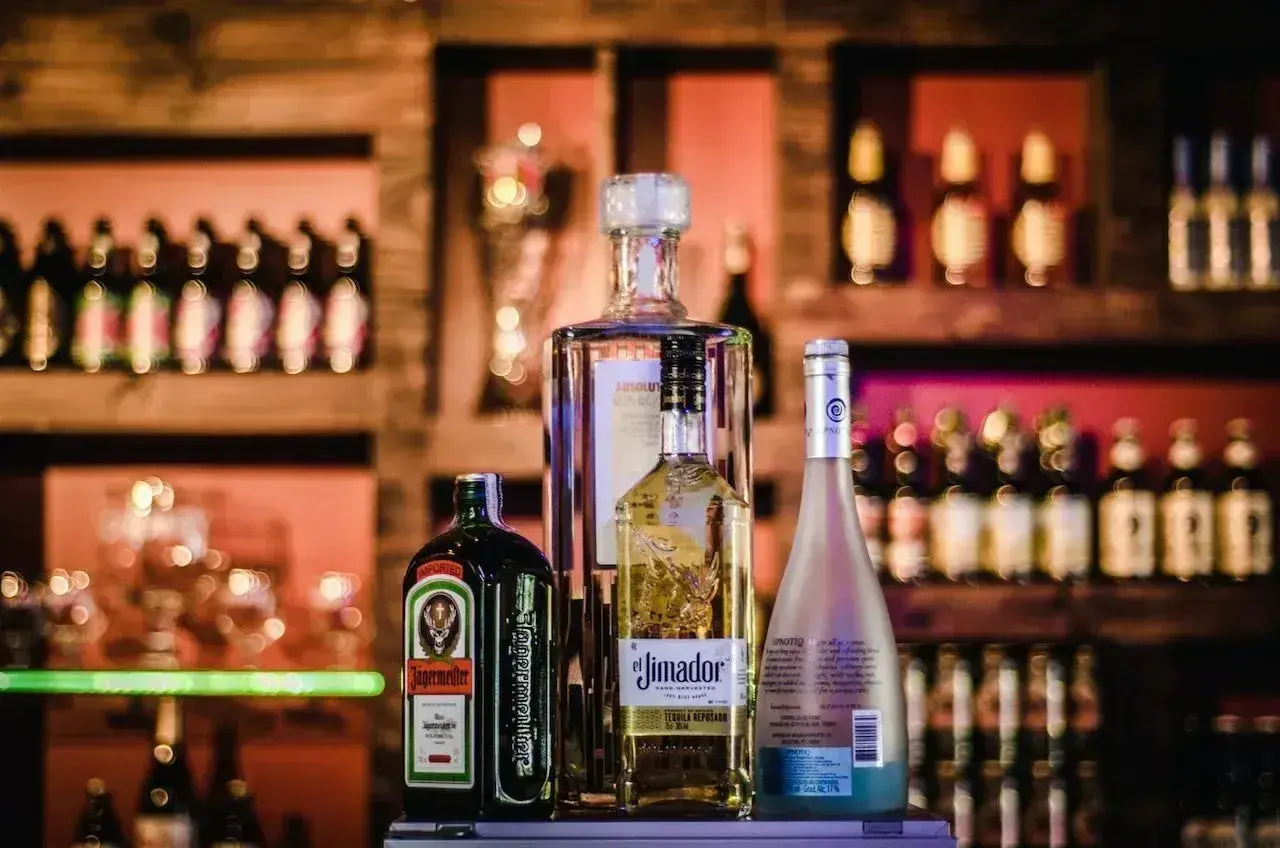 Butelka Jägermeistera, z etykietą informującą o zawartości alkoholu, stoi obok innych alkoholi.