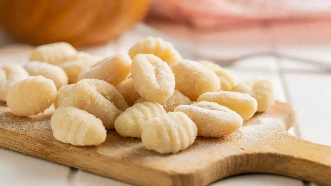 Gnocchis faits maison sur une planche en bois. La question "quelle pomme de terre pour gnocchi" est résolue avec ces petites bouchées parfaites.