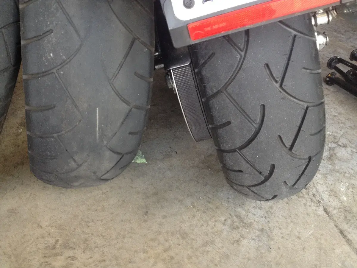 Dos ruedas de moto, una rueda moto gastada con dibujo casi liso y otra con más surcos, sobre suelo de hormigón.