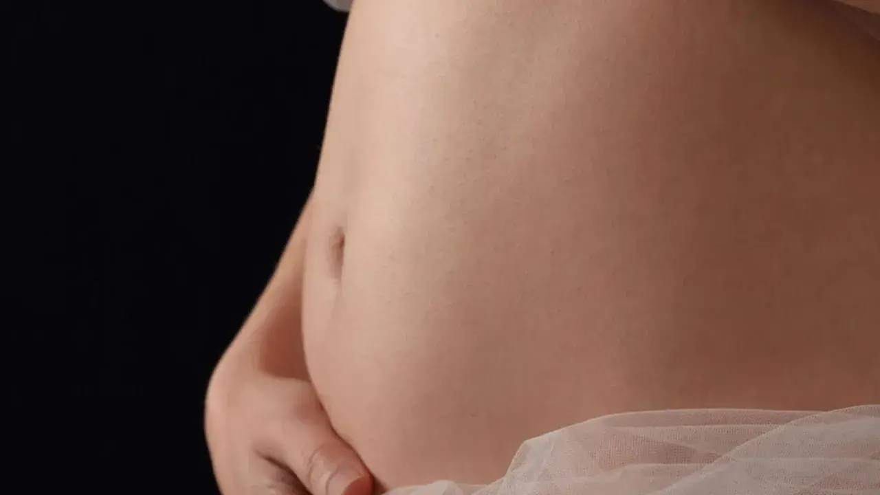 Primo piano di una pancia in gravidanza, che mostra la sua crescita settimana per settimana.