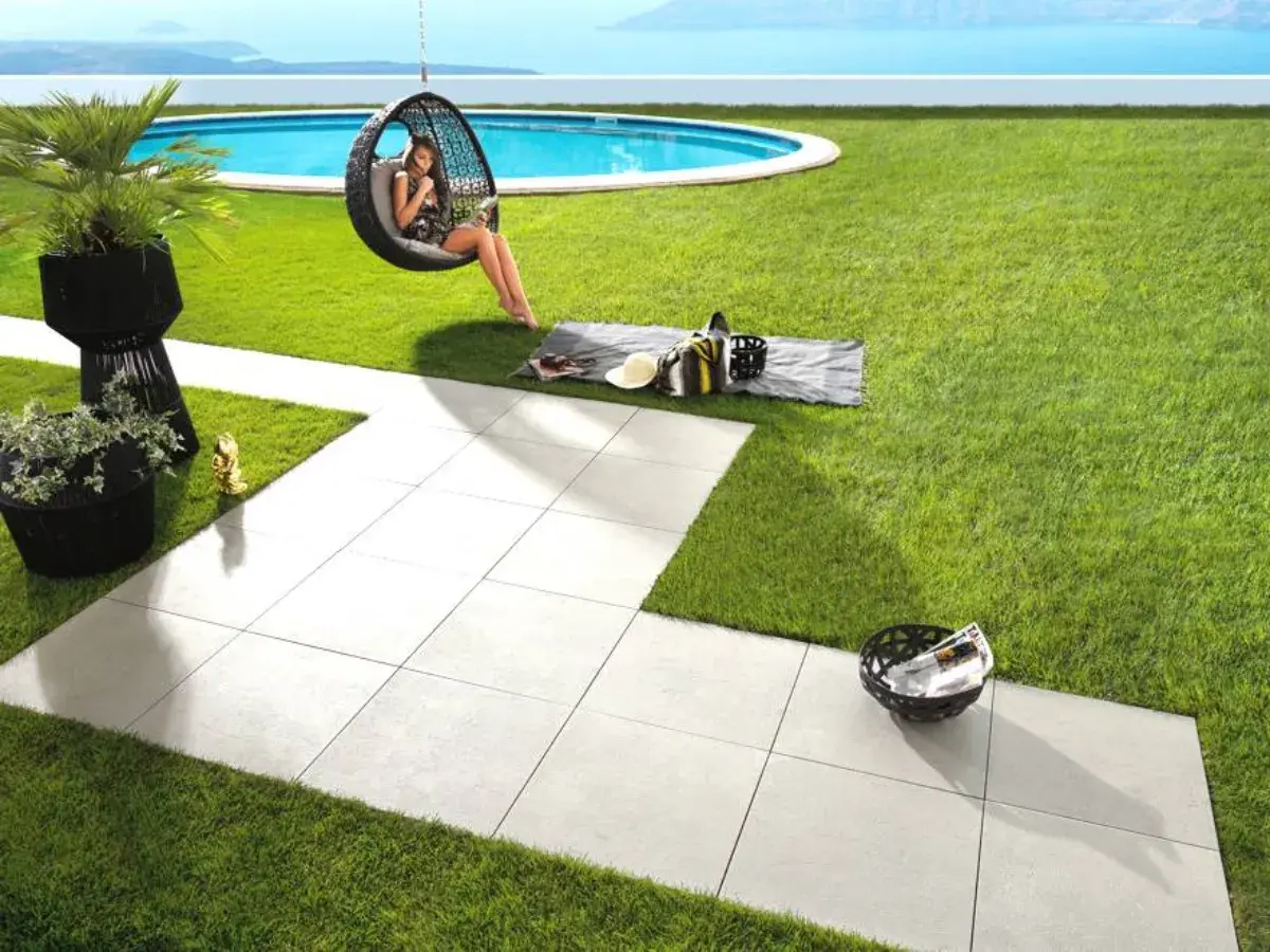 Posa di un pavimento in gres porcellanato con uno spessore ideale per esterni, che crea un'area relax con piscina e vista mare.