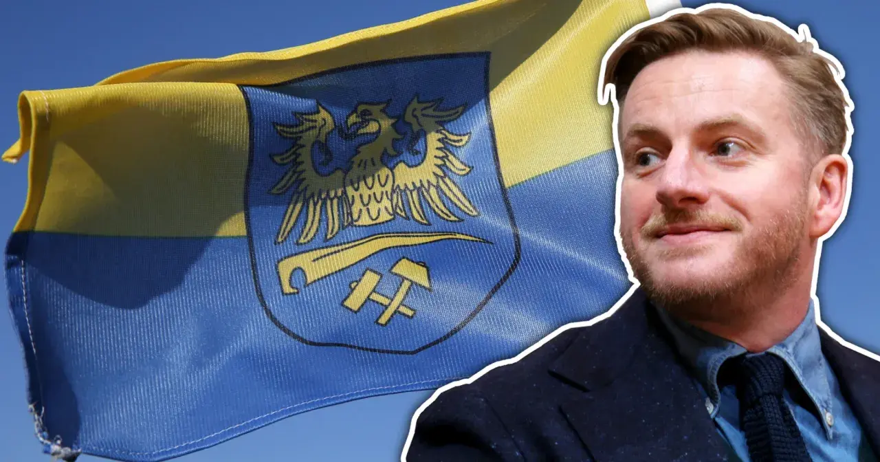 Szczepan Twardoch na tle flagi z godłem Górnego Śląska.