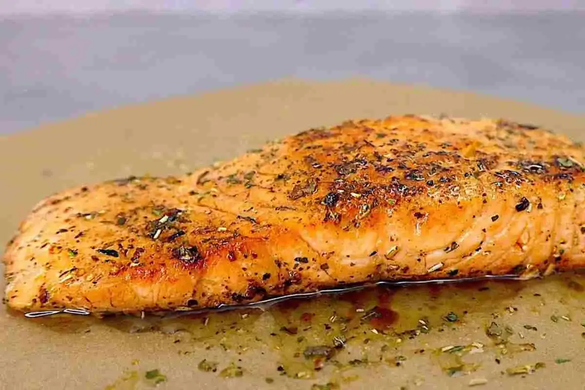 Succulento salmone in padella, dorato e profumato con erbe aromatiche, adagiato su carta da forno.