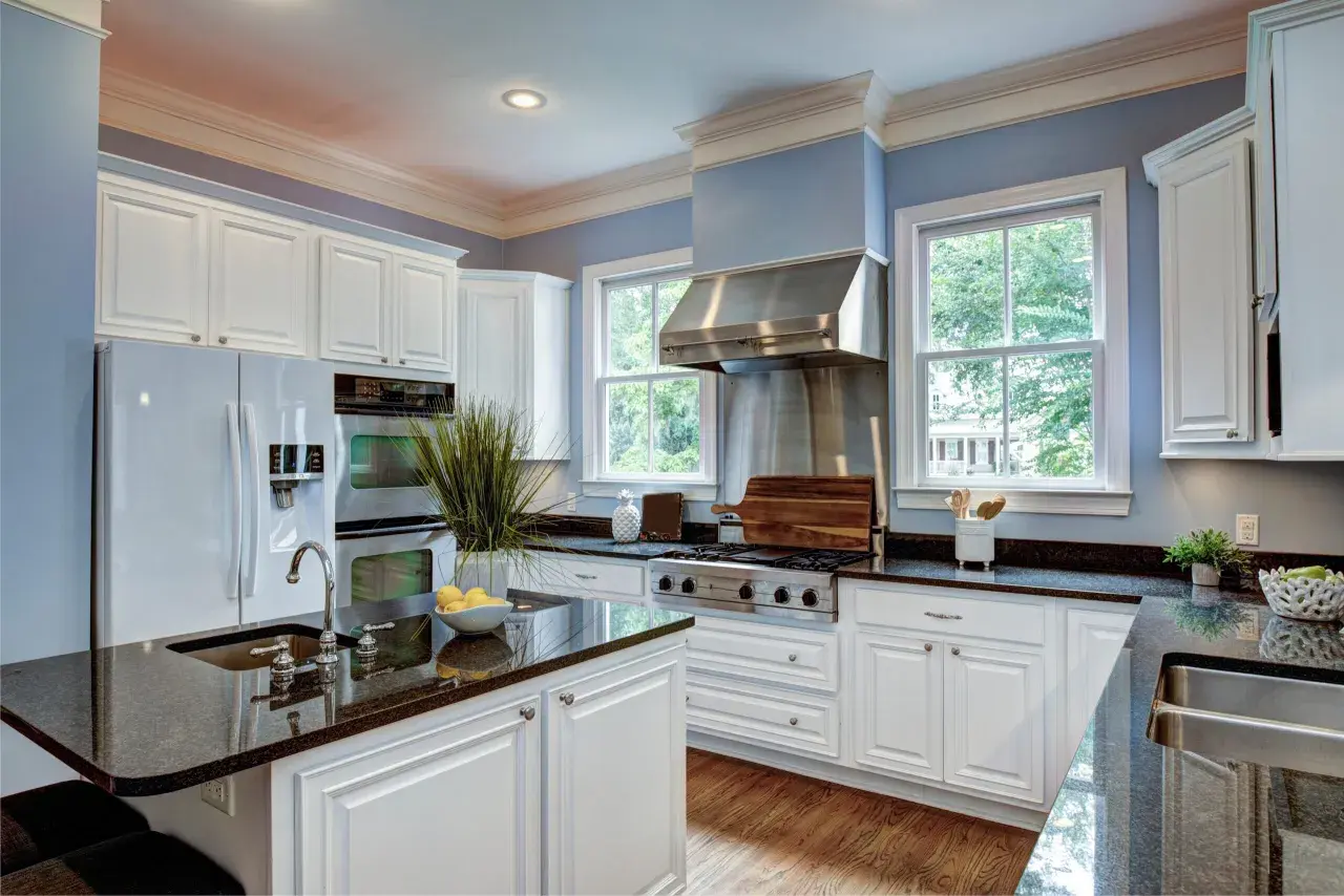 A bright kitchen with white cabinets and granite countertops. Learn how to care for granite to keep it looking its best.