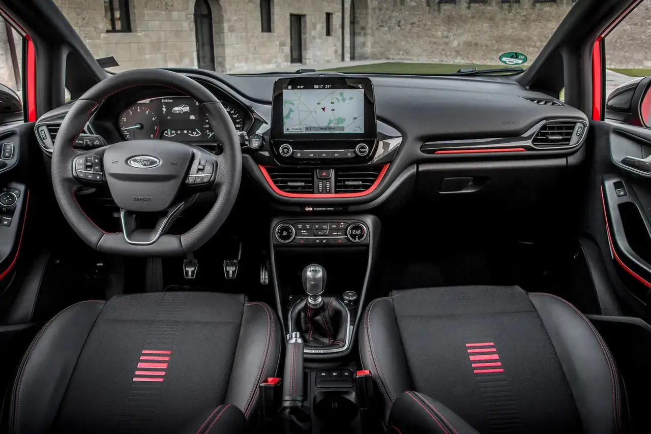 Interior deportivo del Ford Fiesta ST Line. Volante, asientos y detalles rojos resaltan en este habitáculo moderno.