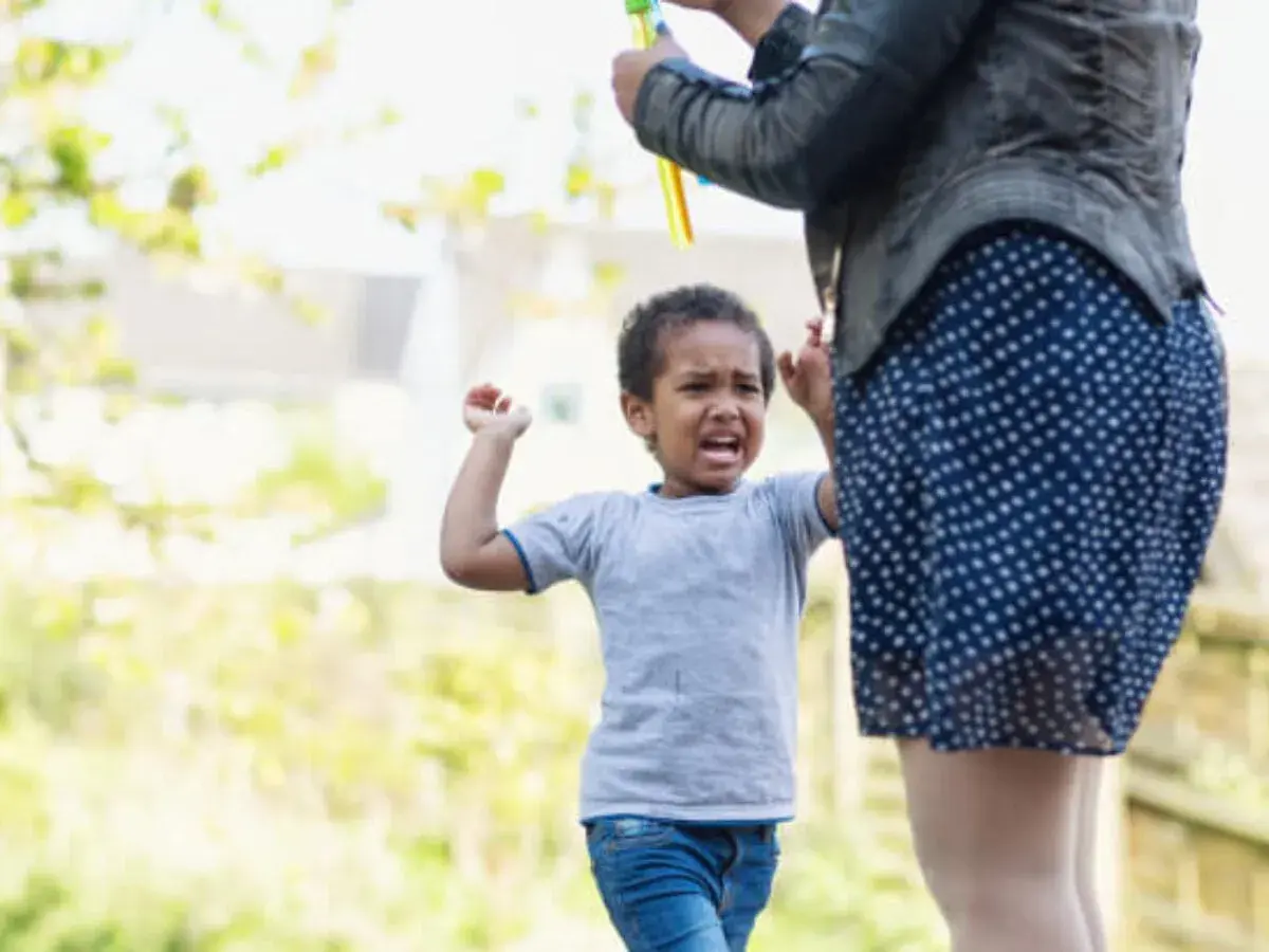 Un niño de 4 años, mi hijo, no obedece y pega. Llora y se enfada mientras su madre intenta calmarlo.