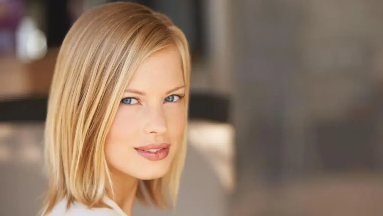 Kobieta z blond włosami w modnym clavi cut, z niebieskimi oczami i delikatnym uśmiechem.