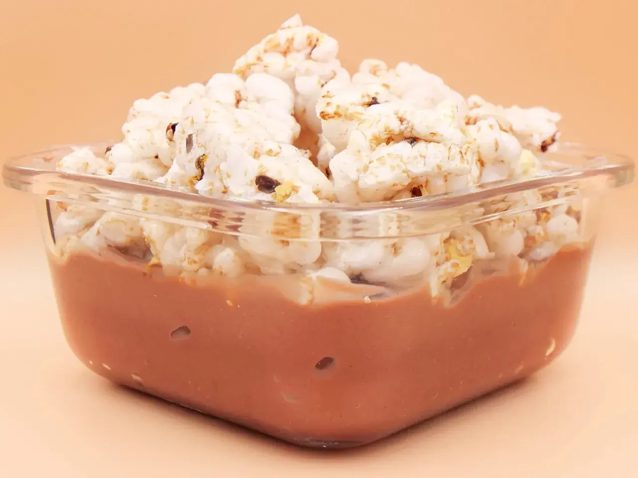 Pudding ryżowy fit w szklanej miseczce, przykryty chrupkami ryżowymi. Idealny na lekki deser.