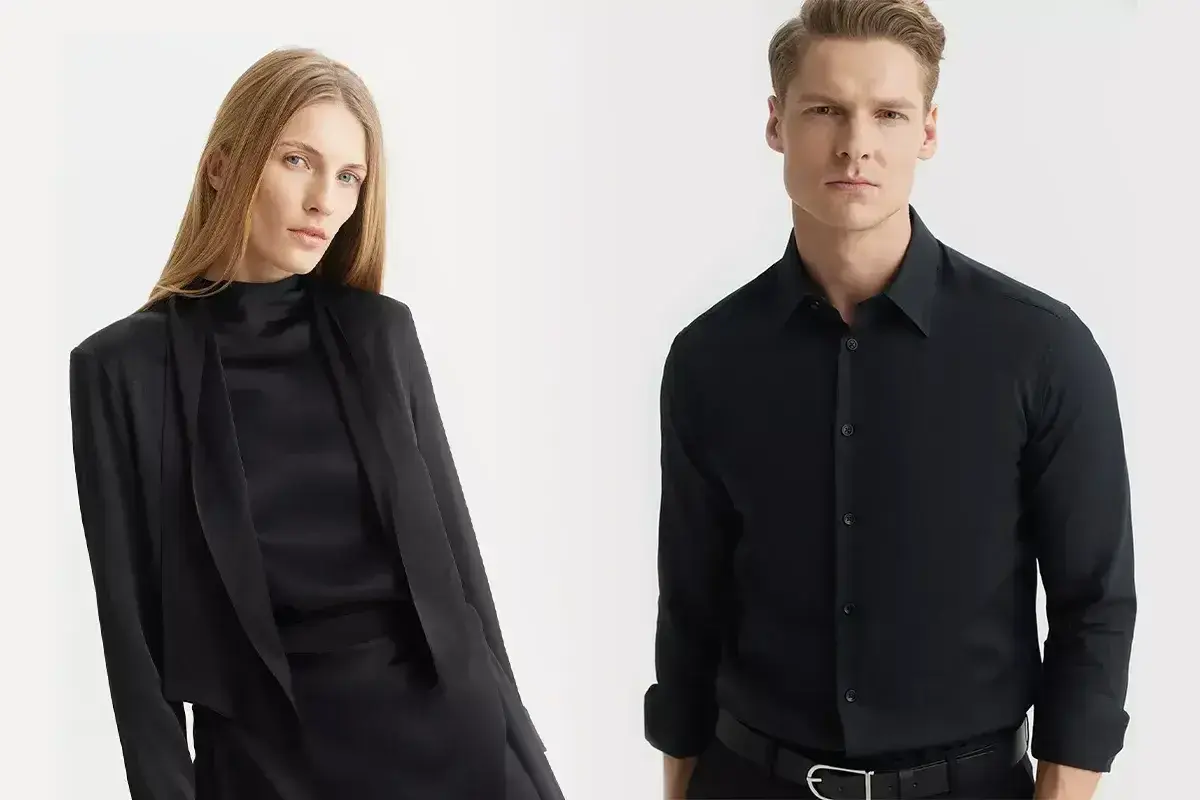 Elegancka kobieta w czarnej stylizacji i mężczyzna w czarnej koszuli. Jakie spodnie do czarnej koszuli? Oto inspiracja.