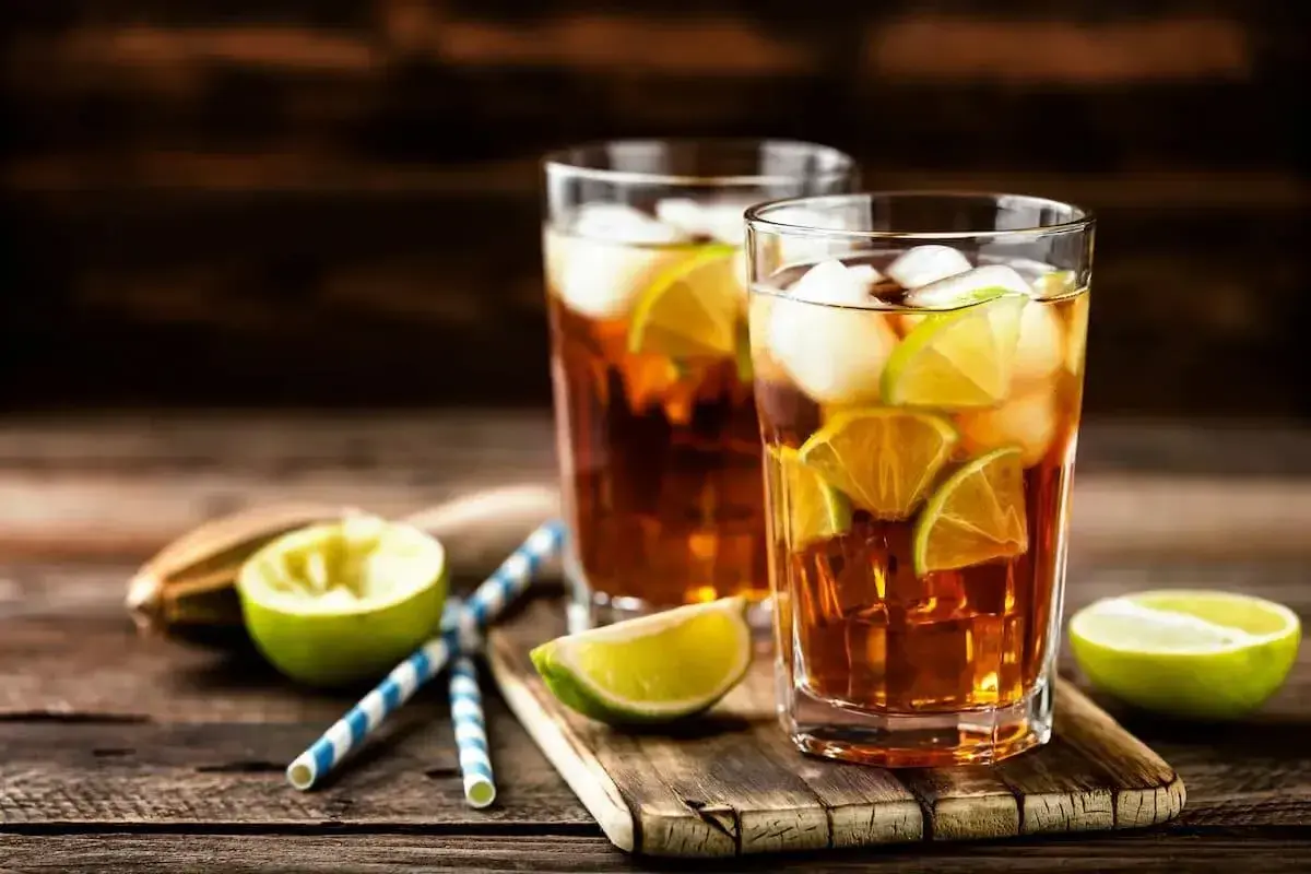 Dwa szklanki z lodem i plasterkami limonki, idealne orzeźwiające drinki na upalny dzień.
