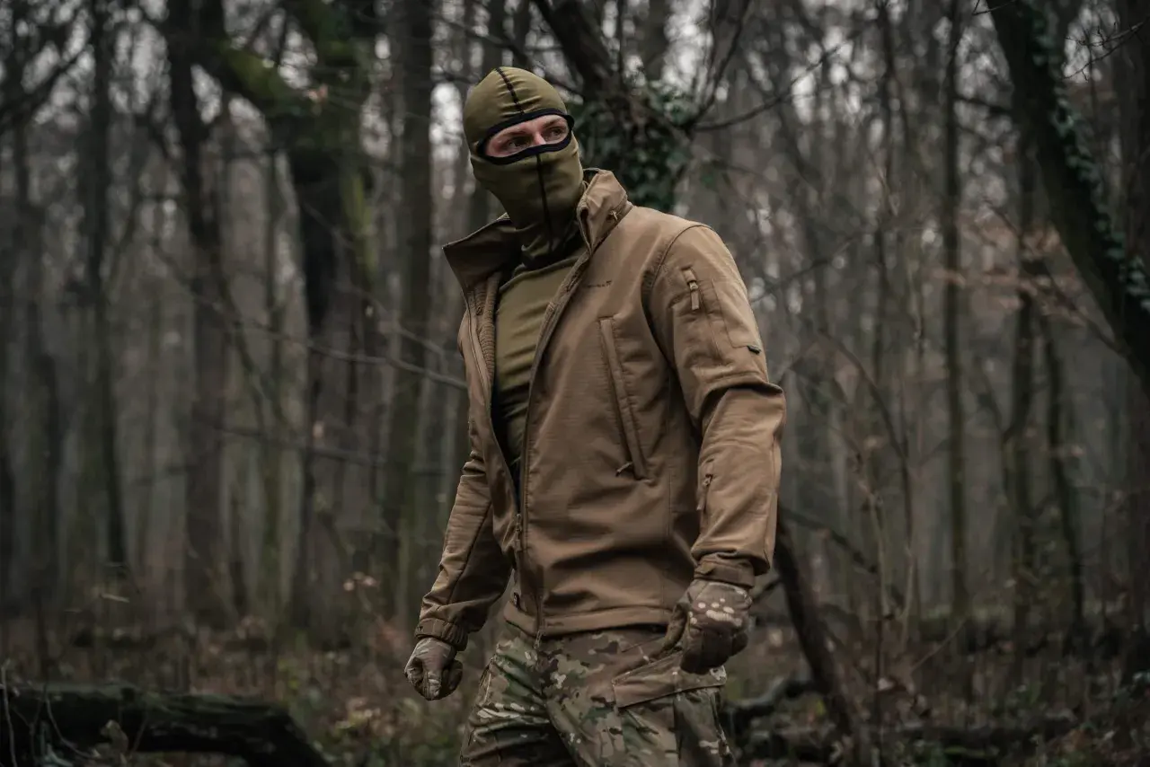 Mężczyzna w lesie, ubrany w kurtkę i maskę, nosi bieliznę termoaktywną Helikon.