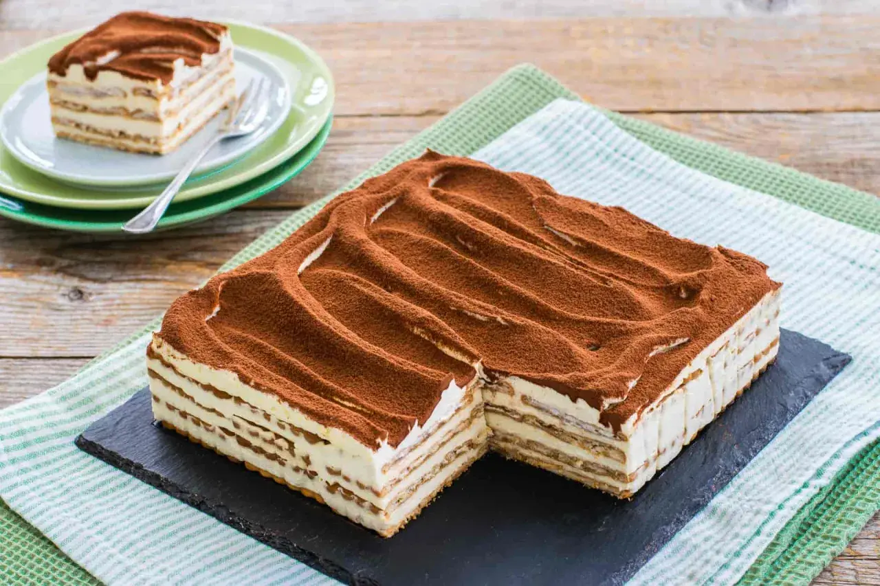 Un invitante tiramisù con oro Saiwa, stratificato e cosparso di cacao, pronto per essere gustato.