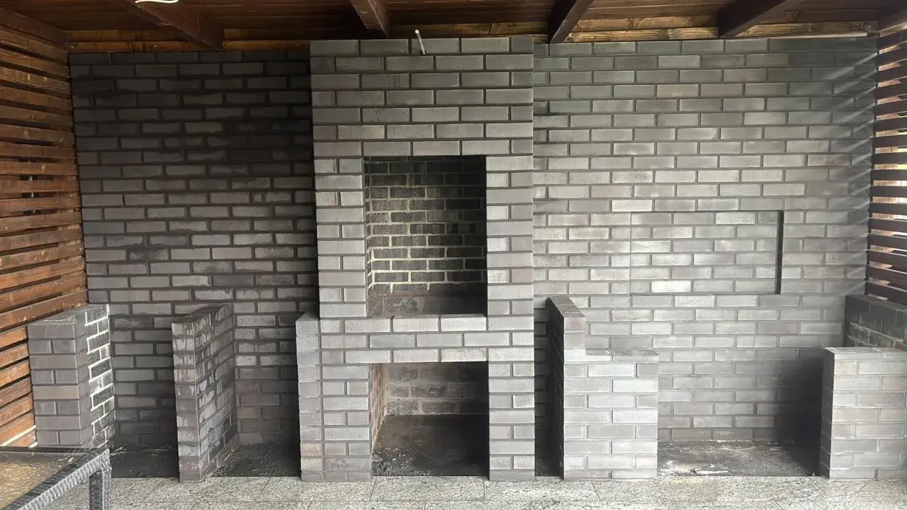 Nowy, murowany prosty grill z cegły czeka na pierwsze rozpalenie. Wygodny, z miejscem na drewno i akcesoria.