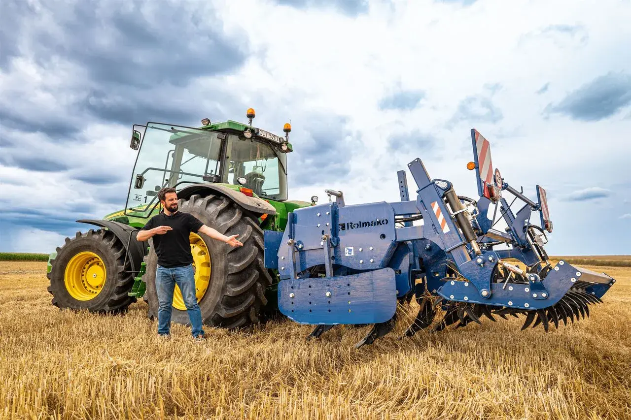 Un homme présente une charrue Rolmako, un outil agricole essentiel pour préparer les sols. La sep charrue définition est ici illustrée par cet équipement robuste.