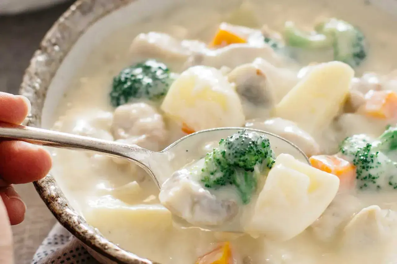 A spoonful of creamy Japanese white stew, filled with tender chicken, potatoes, broccoli, and carrots, ready to be savored.