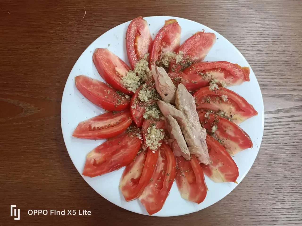 Rodajas de tomate fresco aliñado con ajo picado y hierbas, coronado con trozos de melva. Un plato sencillo y delicioso.