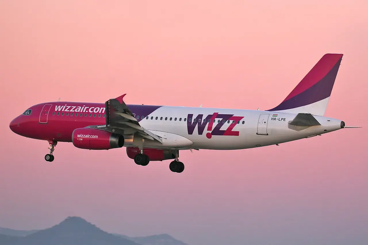 Samolot Wizz Air z różowym dziobem i fioletowym ogonem w locie. Wizz priority to komfort podróży.
