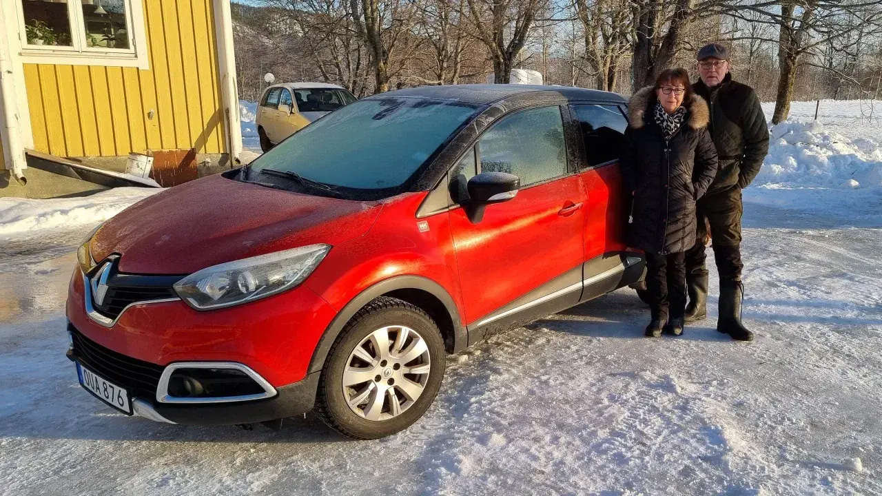 Ett par står bredvid en röd Renault Captur med frost på vindrutan. Kanske ett problem med att starta bilen i kylan?