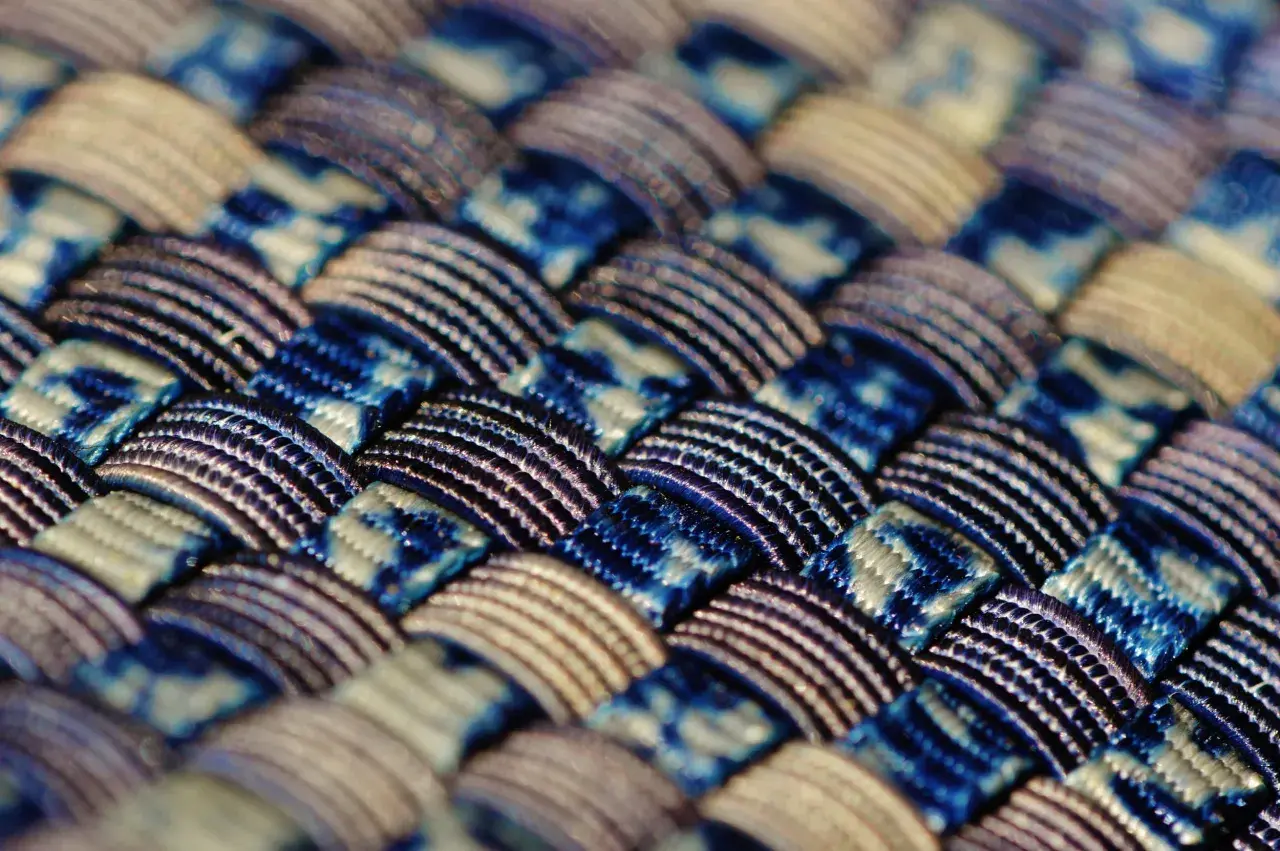 Gros plan sur un tissu intelligent aux motifs bleus et blancs entrelacés, révélant une texture complexe et des fils brillants.