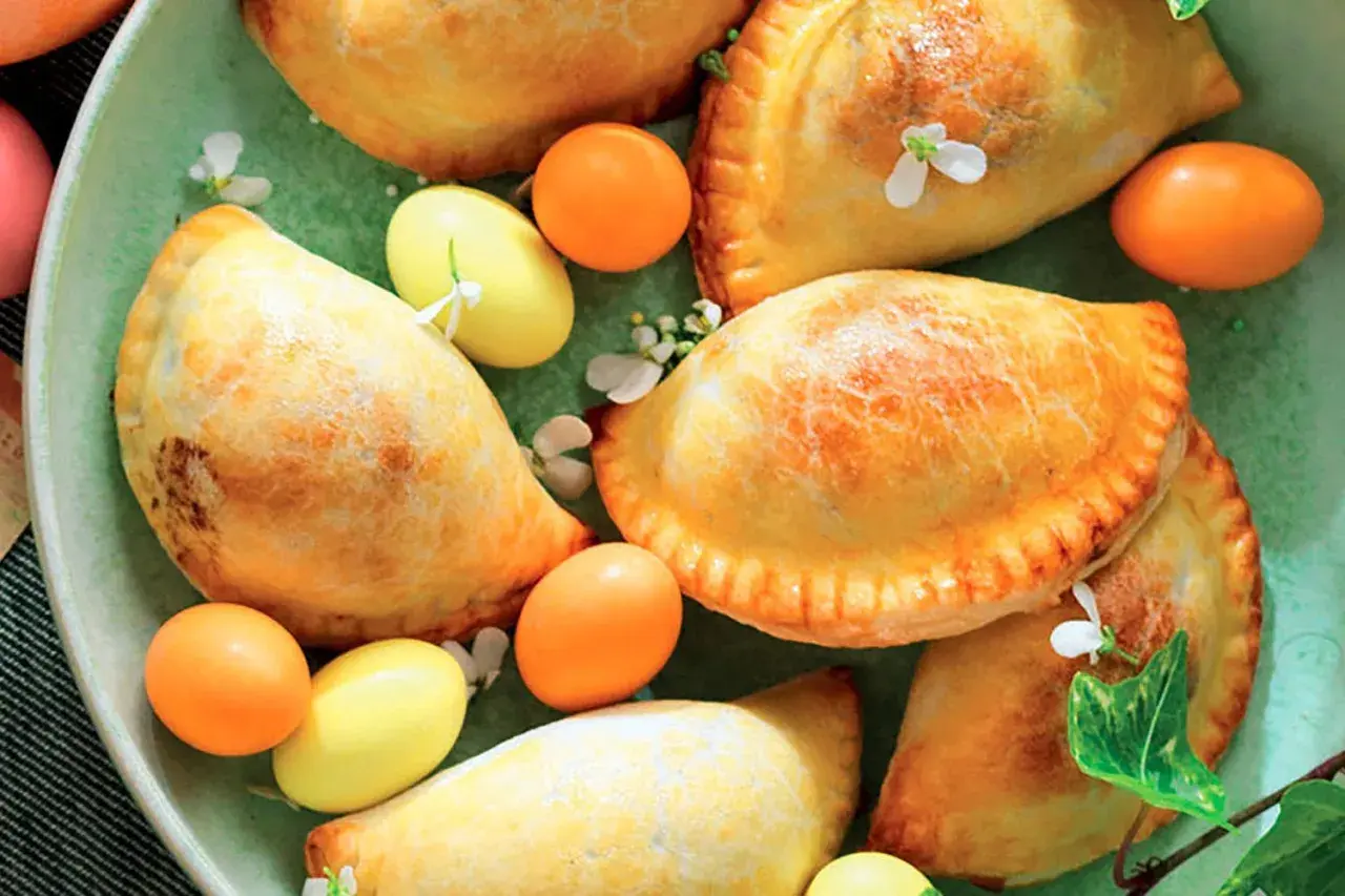 Nepitelle calabresi ricetta originale: dolcetti dorati ripieni, decorati con uova colorate e fiori, un'esplosione di sapori autentici.