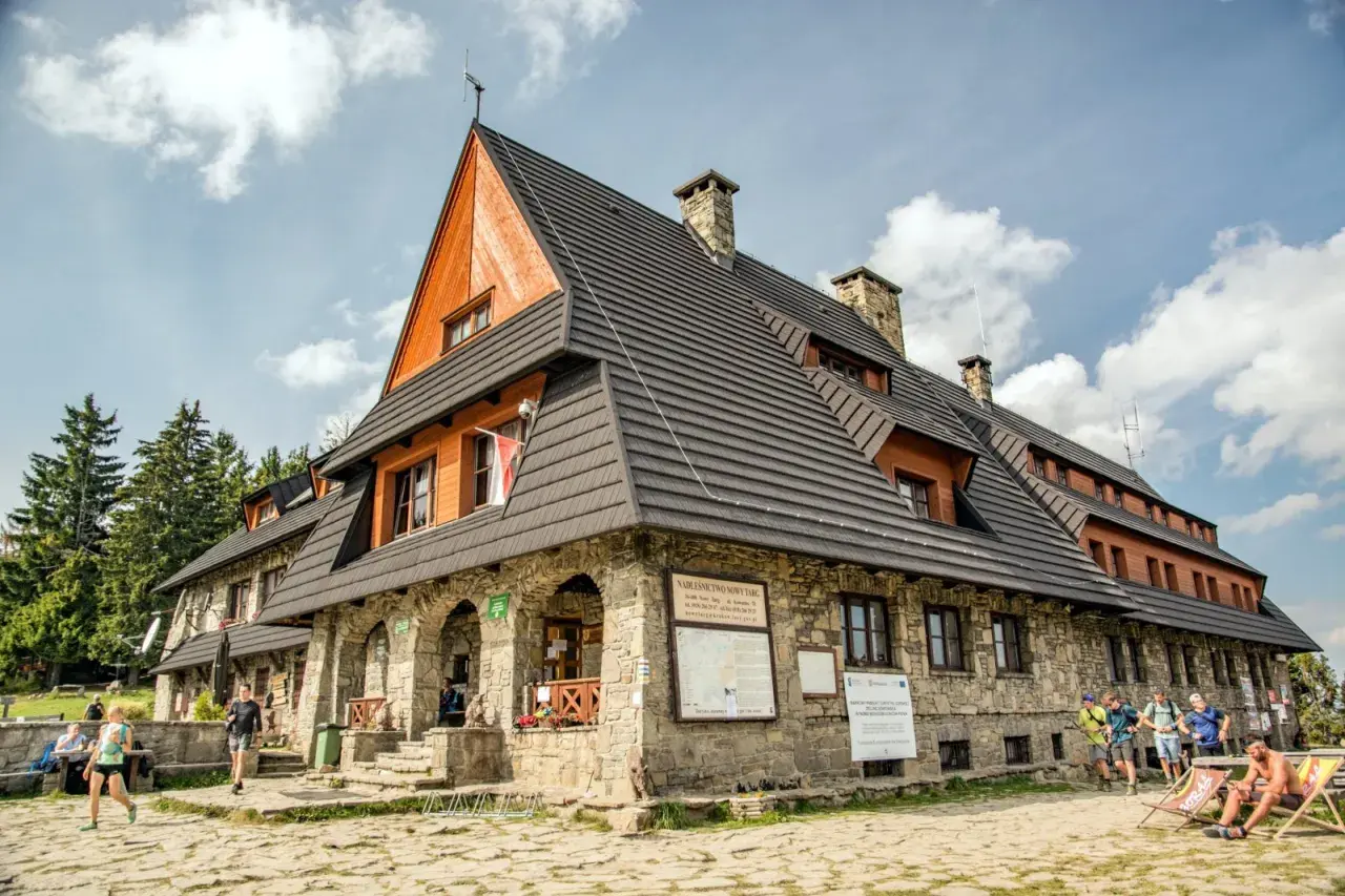 Schronisko PTTK na Turbaczu, popularne wśród turystów z Nowego Targu, z kamienną fasadą i drewnianymi elementami.