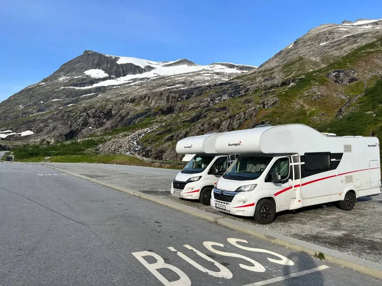 Dwa kampery zaparkowane na tle norweskich gór. Idealne na podróż kamperem w 2 tygodnie po Norwegii.