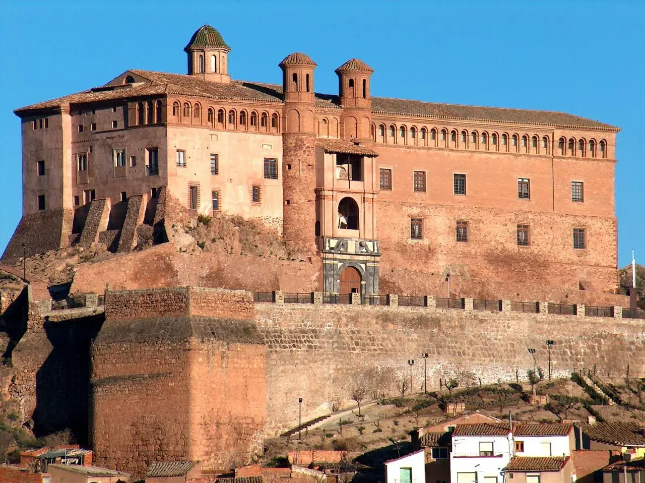 Imponente castillo de ladrillo rojo, con torres y cúpulas, coronando una colina. Un lugar perfecto para imaginar el festival de los castillos.