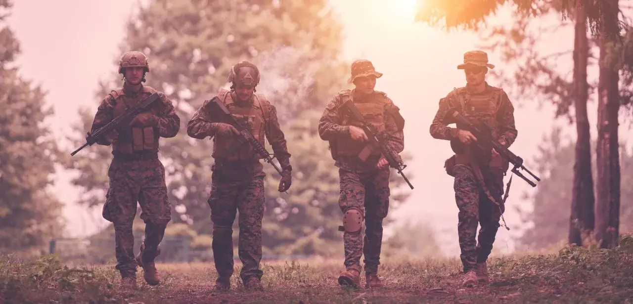 Czterech żołnierzy w kamuflażu, z karabinami, idzie przez las. Czy to przygotowanie do "Escape from Tarkov wymagania"?