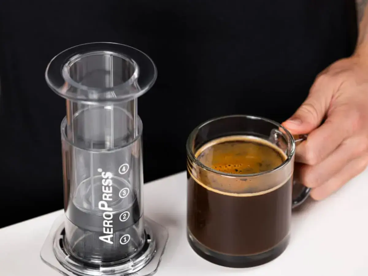 AeroPress gotowy do zaparzenia idealnego espresso. Obok filiżanka aromatycznej kawy.