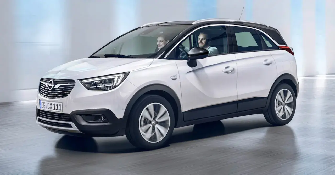 Biały Opel Crossland z parą uśmiechniętych ludzi w środku. Sprawdź atrakcyjną opel crossland cena!