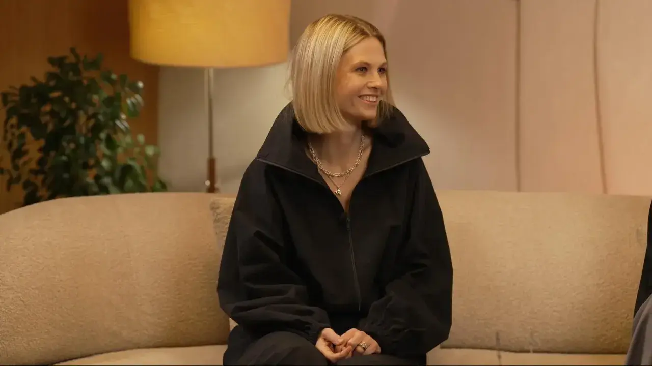 Uśmiechnięta Anna Karczmarczyk w czarnej bluzie, siedząca na kanapie. Jej filmy, seriale i programy to świetna rozrywka.