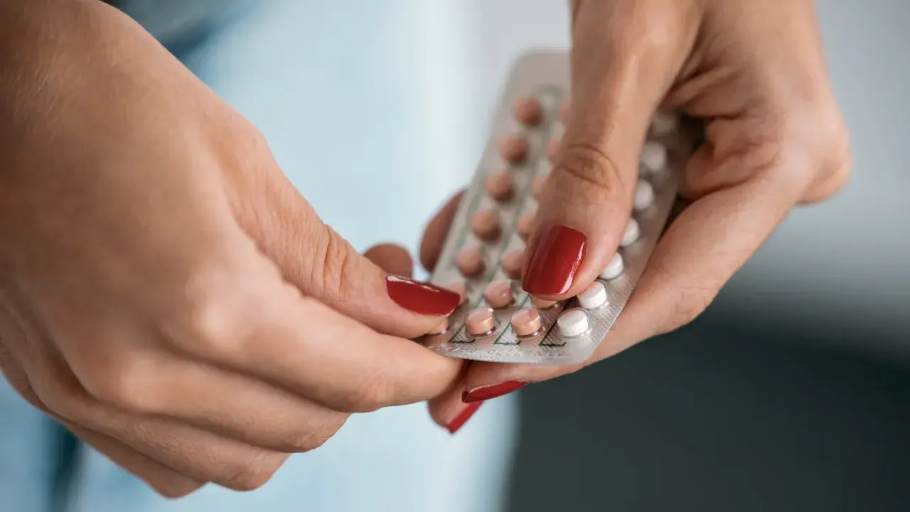 Hände halten eine Blisterpackung mit Pillen, darunter eine Drospirenon Pille.