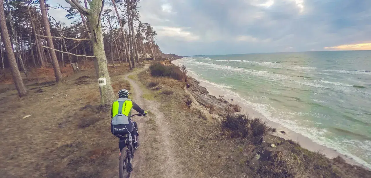 Rowerzysta na ścieżce przy klifie, w tle morze. Trasa rowerowa w okolicach Słupska.