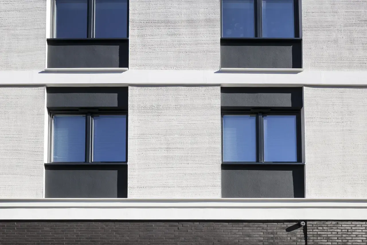 Moderne Fassade mit Klinker und Putz. Fenster mit dunklen Rahmen und blauen Scheiben.