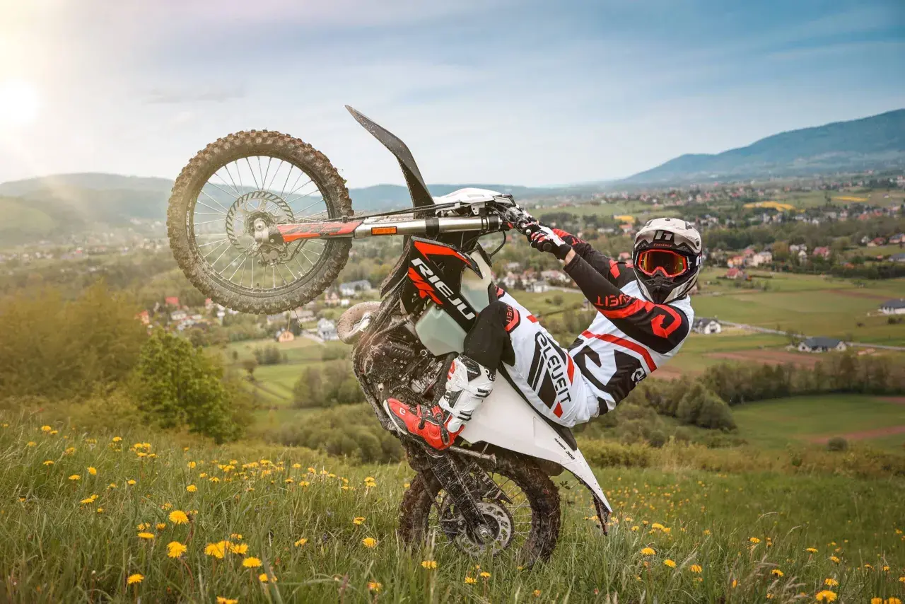Motocyklista wykonuje jazdę na jednym kole na tle malowniczego krajobrazu. Uważaj, bo taka jazda na jednym kole może skończyć się mandatem!