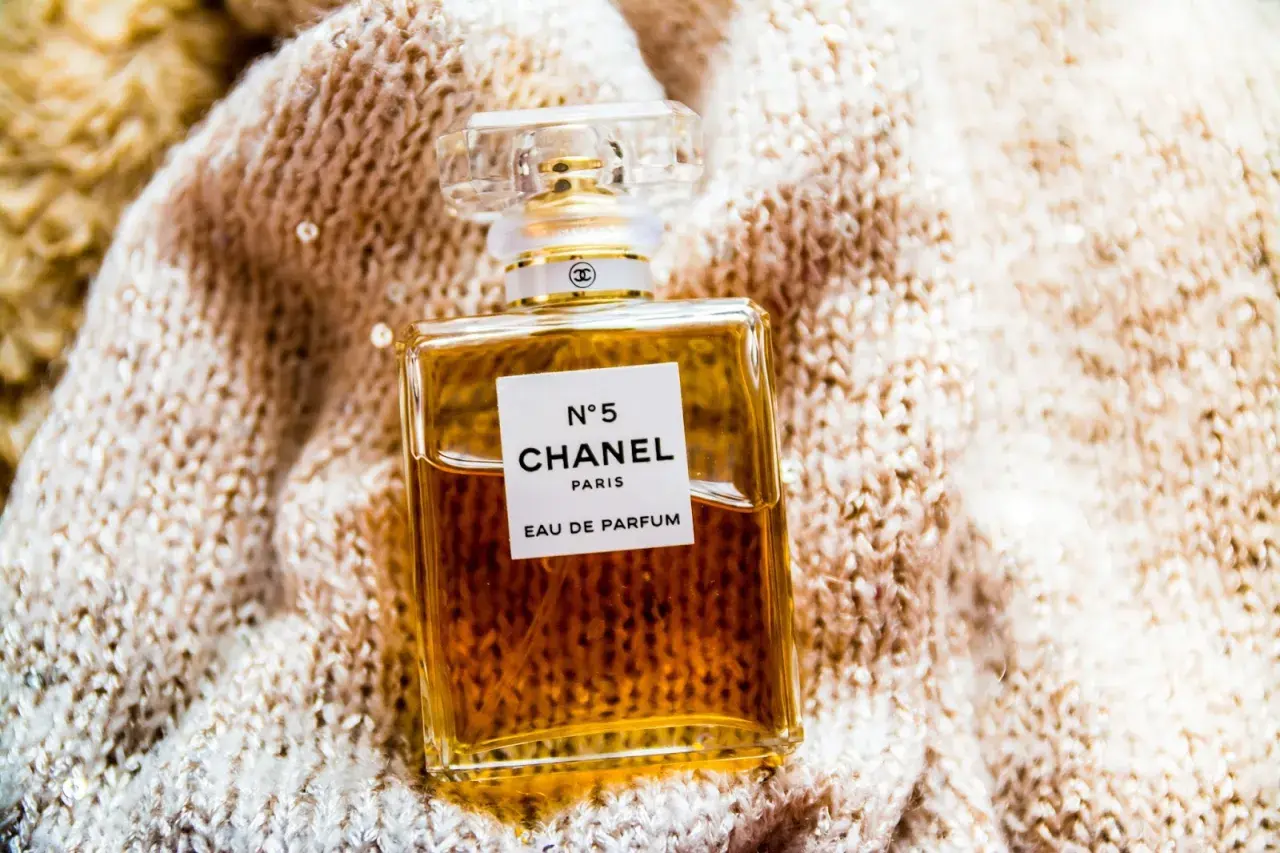Elegancka butelka Chanel N°5 Eau de Parfum na miękkim, błyszczącym swetrze.