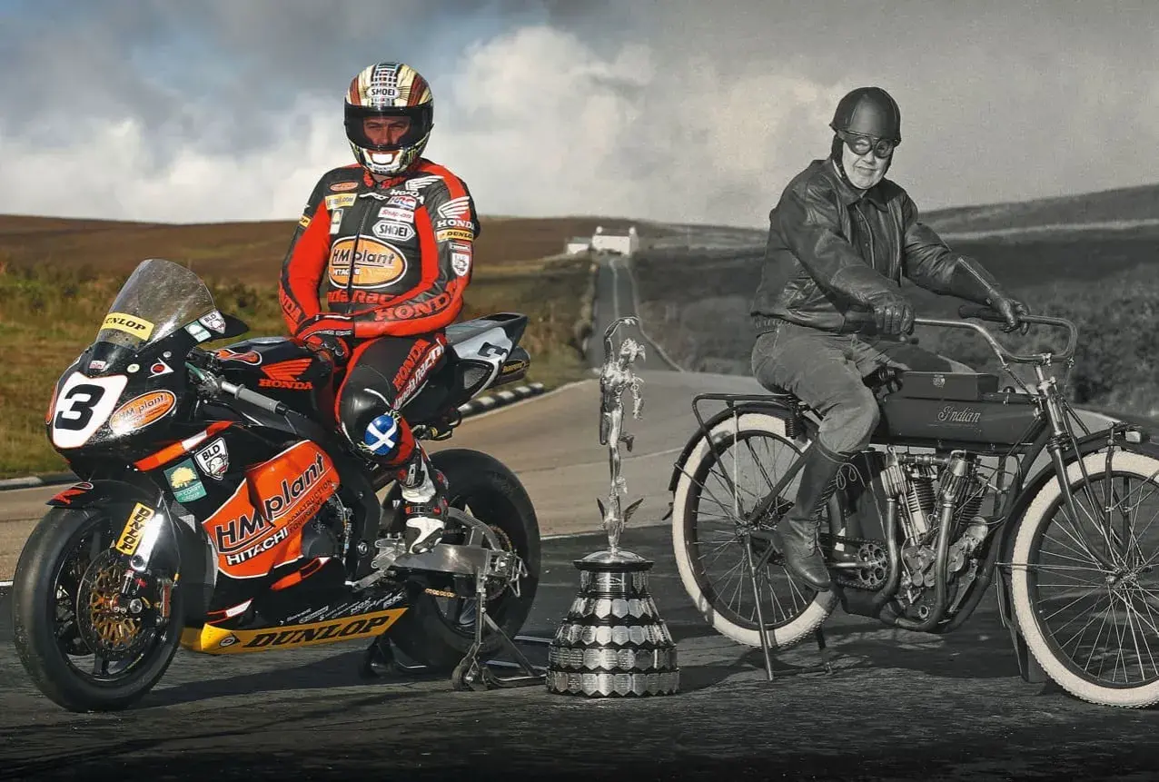 Conor Cummins junto a su moto de carreras y un trofeo, junto a un piloto histórico en una Indian.