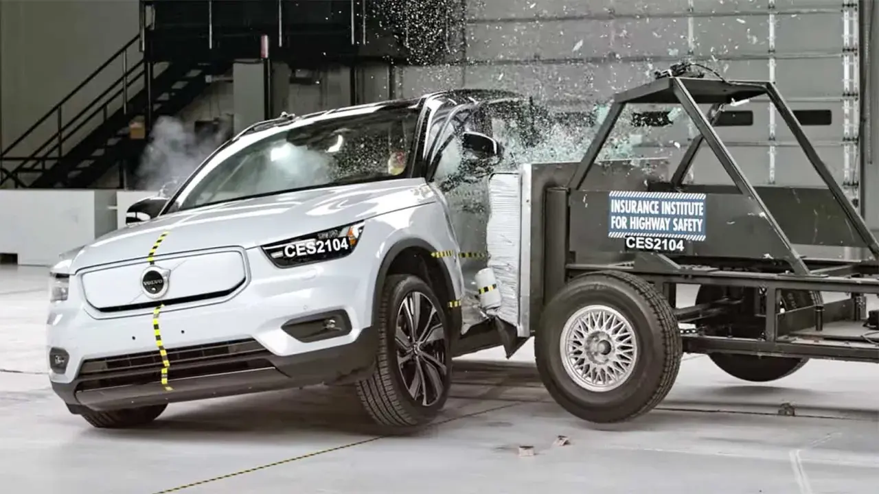 En vit Volvo XC40 krocktestas mot en barriär. Glas splittras och bilen deformeras vid kollisionen.