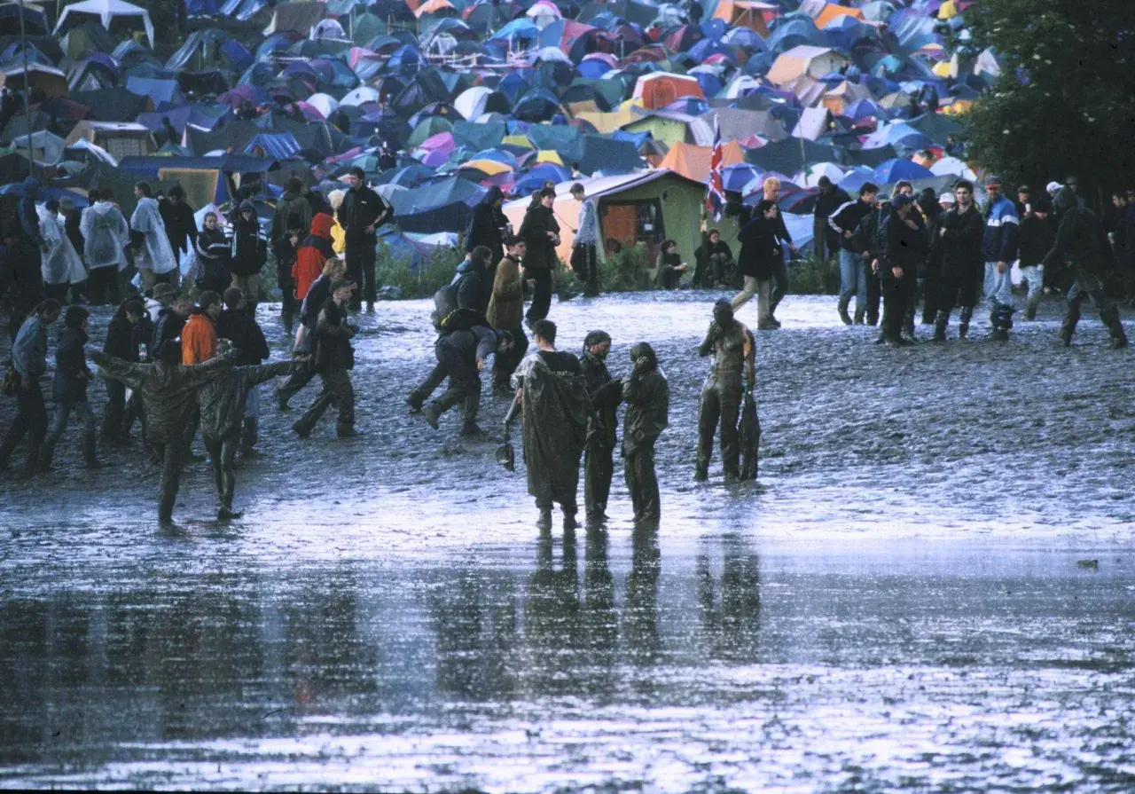 Muddy field with tents and people at Radiohead's iconic Glastonbury 1997 performance.