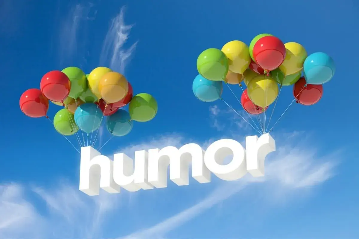 Färgglada ballonger bär upp ordet "humor" i luften. En härlig skrift med humor som svävar mot en blå himmel.
