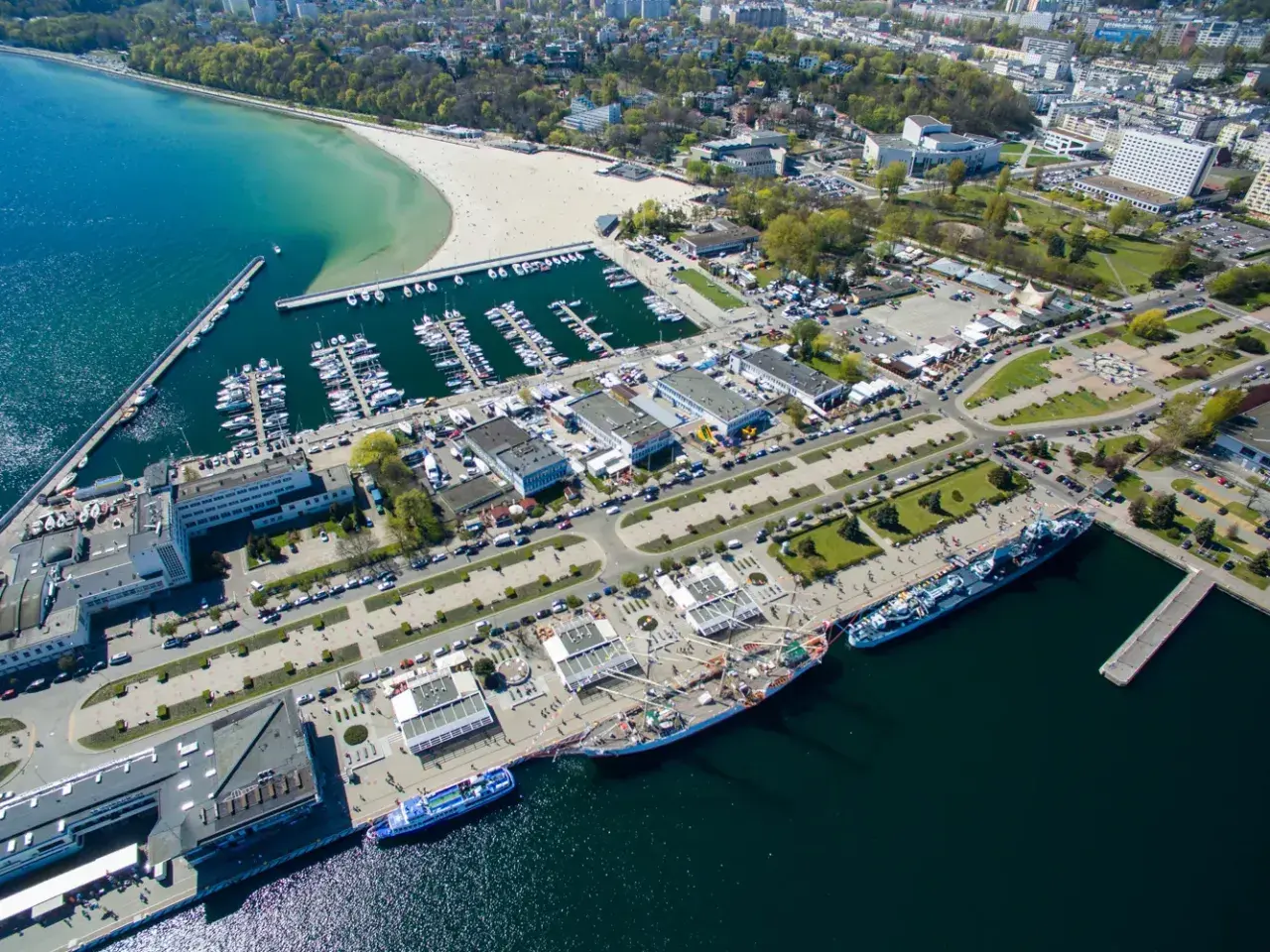 Gdynia co zobaczyć: malownicza plaża, pełny jachtów port, statki i miejska panorama. Idealne miejsce na spacer i podziwianie widoków.