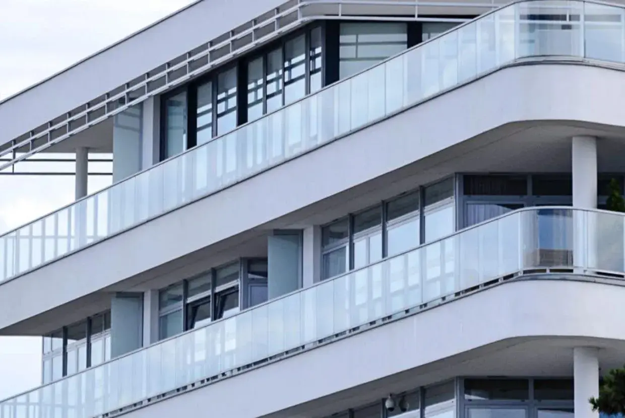 Edificio moderno con balcones y barandillas de cristal, creando una escritura de división horizontal.