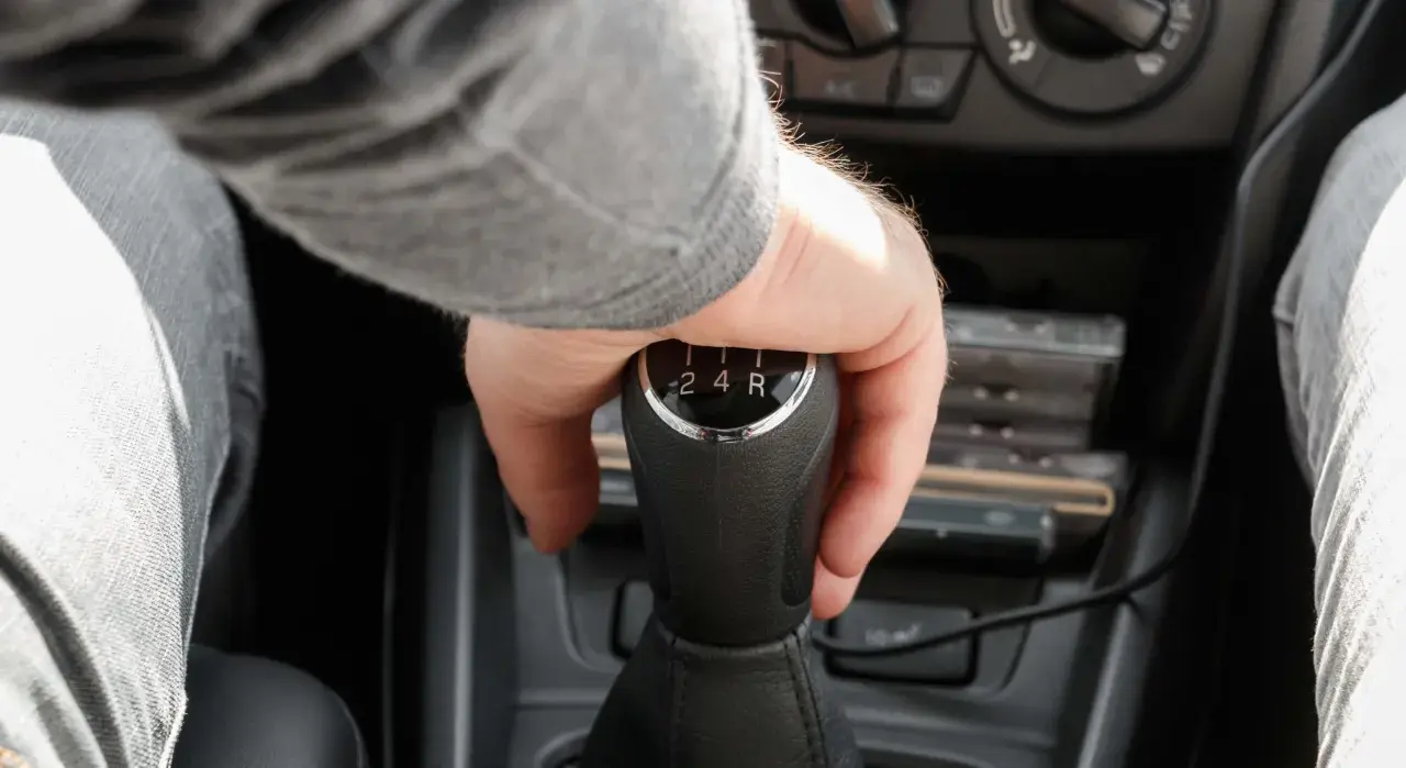 Mano cambiando de marcha en un coche, se escucha un ruido al girar el volante en movimiento a la derecha.