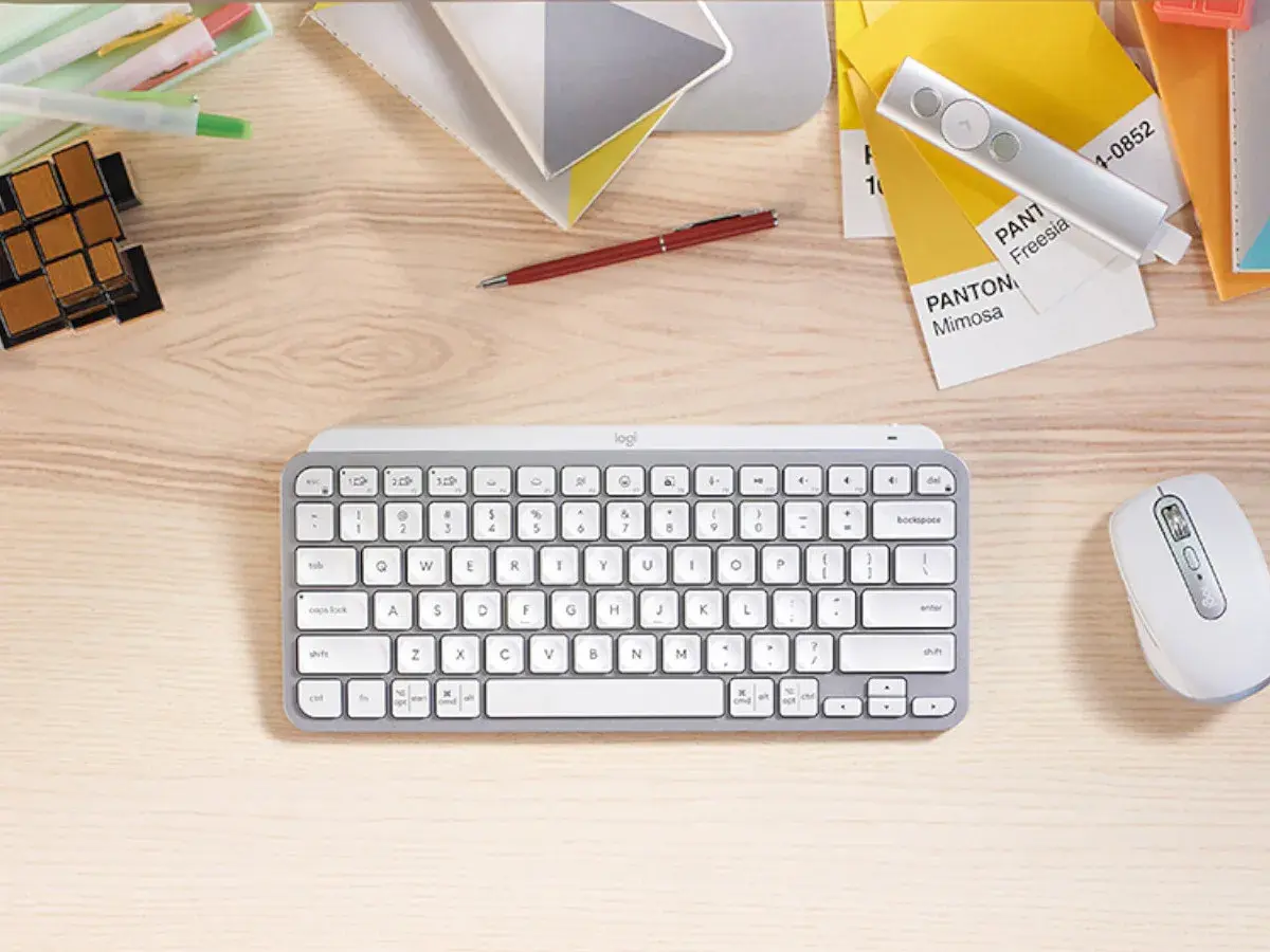 Escritorio con varios tipos de teclado, ratón, bolígrafo, cubos y muestras de color Pantone.